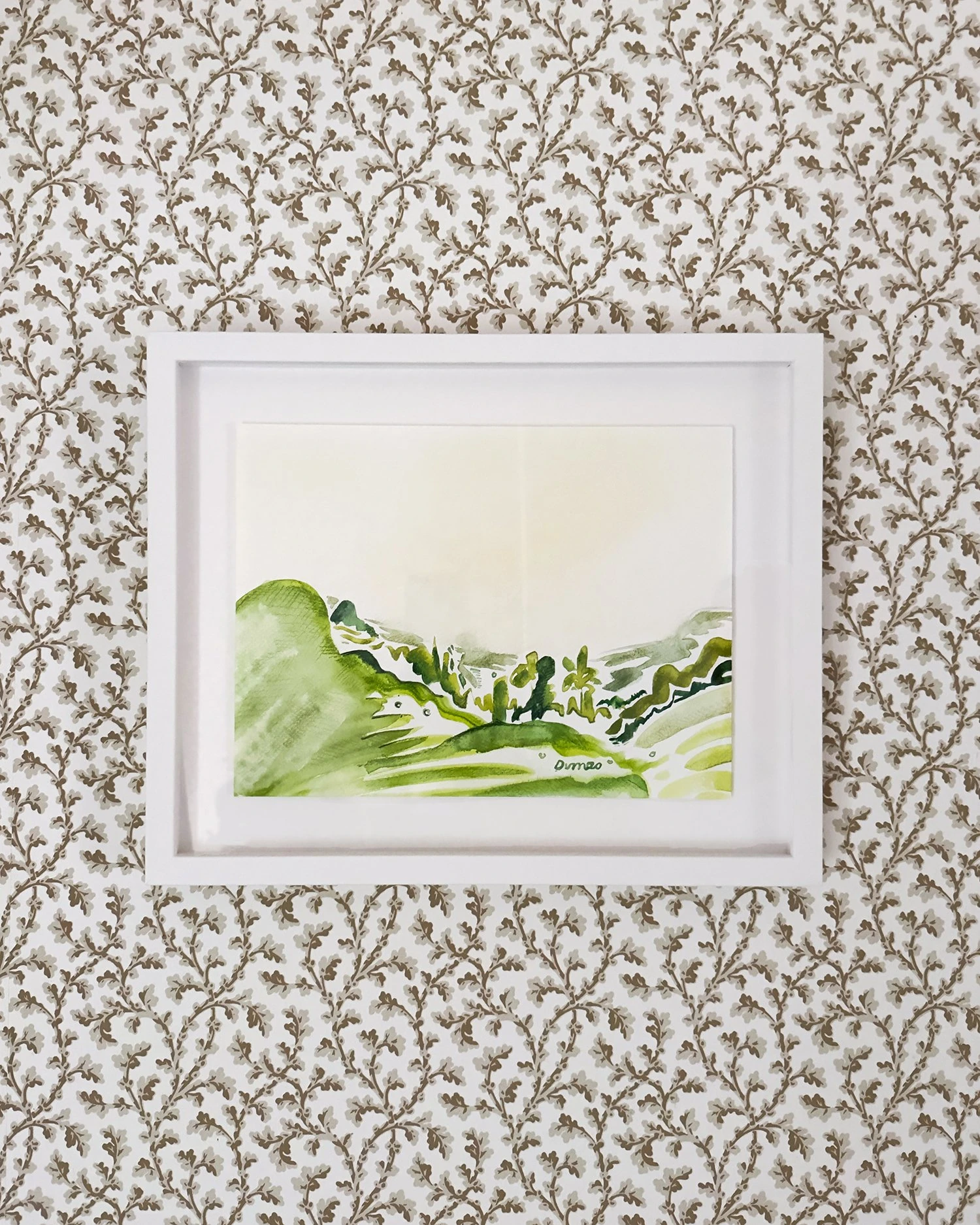 A framed green landscape watercolor hangs against patterned wallpaper.